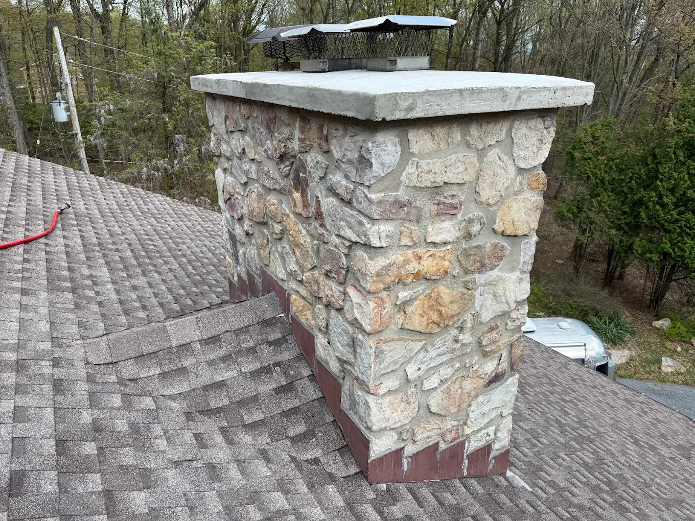 Full view of rebuilt stone chimney with new concrete crown and chimney cap in York PA by LBE Masonry