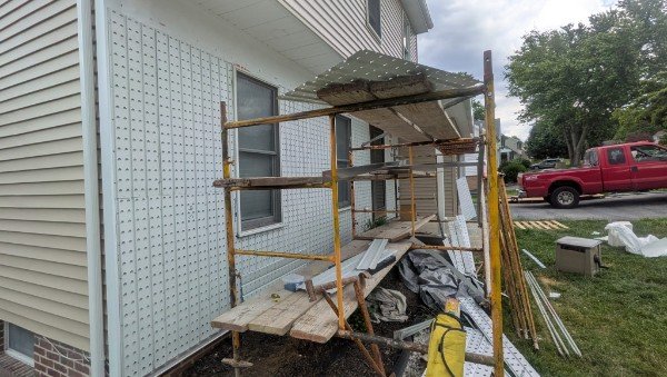 Before: house front wall stripped to Tyvek housewrap with scaffolding during thin brick veneer installation in New Freedom PA
