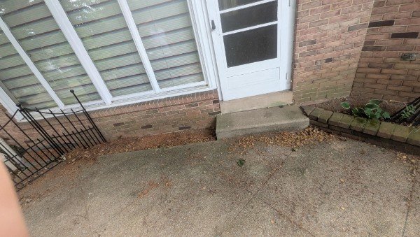 Before: narrow white back door with a small concrete stoop in a brick wall next to white windows, York County PA home
