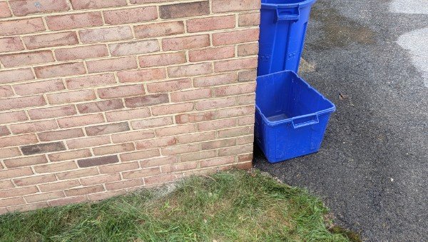 Repointed brick corner beside a driveway with recycling bins, York County PA