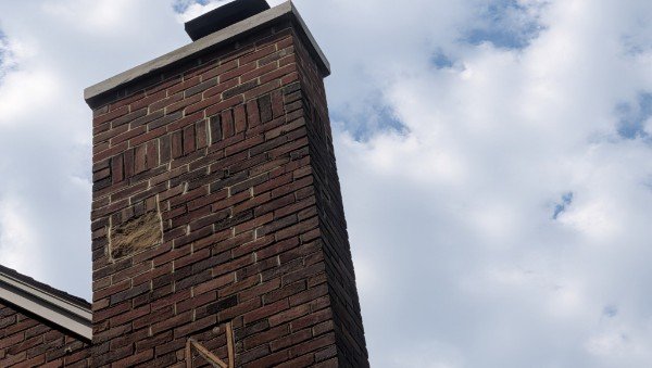 Finished brick chimney seen from the ground after the top was rebuilt by LBE Masonry, with a new concrete crown, metal cap and decorative brick bands, York County PA