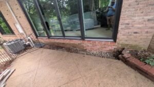 After: brick wall opening widened by LBE Masonry and fitted with a wide black-framed multi-panel glass door, new brick courses below the sill, York County PA