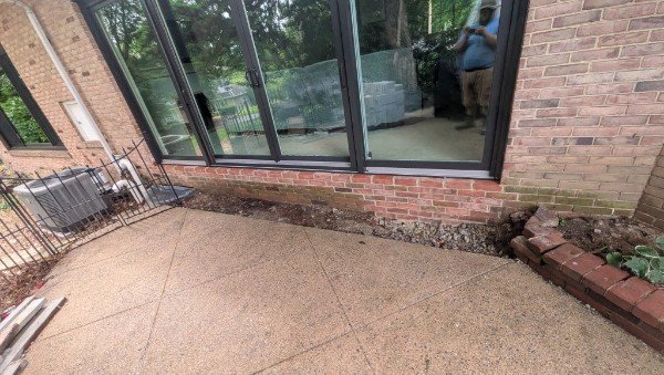 After: brick wall opening widened by LBE Masonry and fitted with a wide black-framed multi-panel glass door, new brick courses below the sill, York County PA